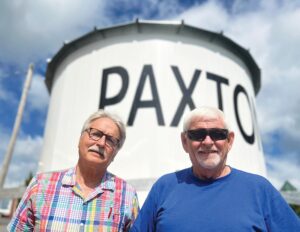 Paxton Foundation President Royce Baier, left, and Stan Foster pose with a replica of Paxton’s original water tank, which is expected to be hoisted by a crane and placed atop the city’s 138-year-old, 80-foot-tall brick water tower behind City Hall downtown around 9 a.m. Wednesday, Aug. 27. The 100 block of South Market Street will be temporarily closed as a result. Will Brumleve/Ford County Chronicle